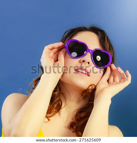 Summer fashion eyes protection concept. Closeup girl long curly hair in violet heart shaped sunglasses on blue