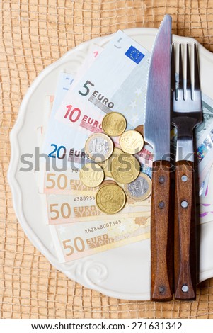 Cost of living, price of food and eating wealth concept. Euro money on kitchen table, plate with cutlery