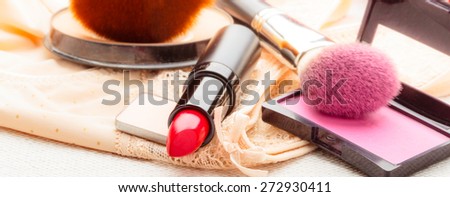 Women beauty concept. Makeup supplies various cosmetics. Red lipstick, powder and rouge cheeks on lace lingerie.
