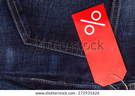 Shopping and sale concept. Closeup red label with percent sign and copy space on navy blue jeans pocket denim cotton material background