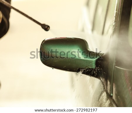 Manual auto wash. dirty car during washing process with foam and pressured water on open air at service station