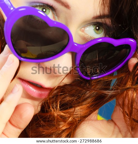 Summer fashion eyes protection concept. Closeup girl long curly hair in violet heart shaped sunglasses on blue
