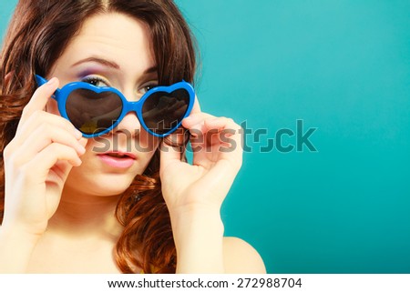 Summer fashion eyes protection concept. Closeup girl long curly hair in blue heart shaped sunglasses