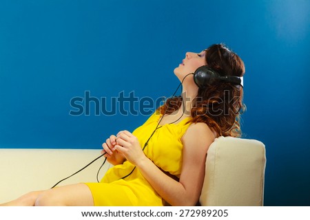 Young people leisure relax concept. Closeup teen cute girl in big headphones listening music mp3 relaxing on blue background