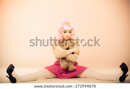 Mental disorder concept. Young childlike woman wearing like puppet doll holding teddy bear toy studio shot