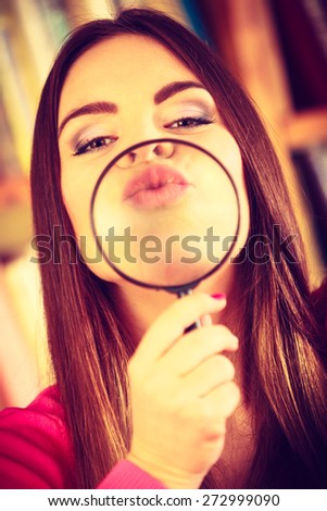 Investigation exploration education concept. Closeup funny woman face, girl holding on lips magnifying glass loupe. Instagram filter