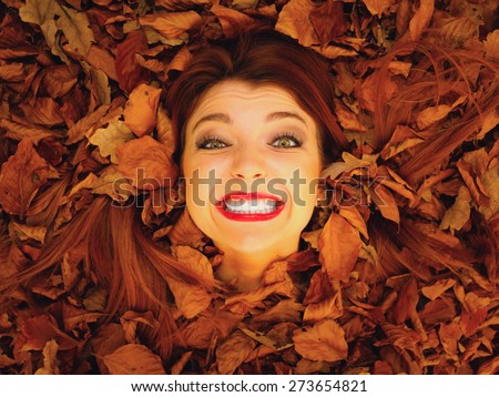 Ecology earth, eco friendly and love nature concept. Portrait young redhaired woman cover in autumn orange leaves. High angle perspective view.