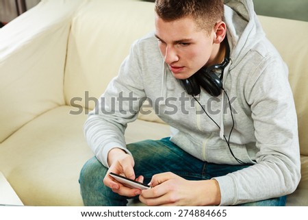 Modern technologies connection leisure concept. Young handsome man relaxing on couch with headphones smartphone at home