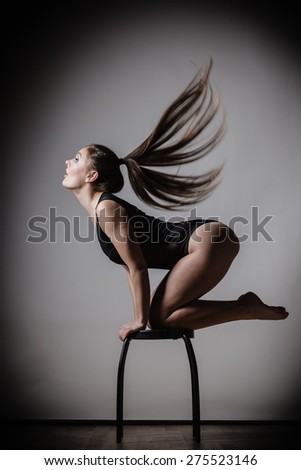 Bodybuilding. Atletic woman fit slim body posing with hair blowing on dark background
