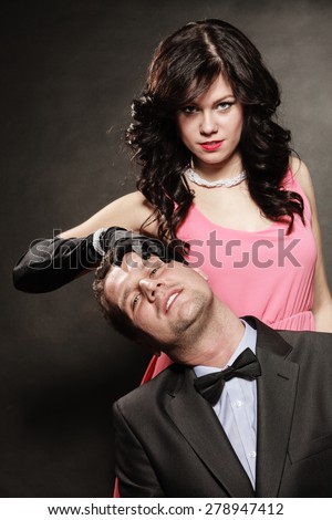 Woman in control of man, sexy female controls her guy. Studio shot on black grey background.