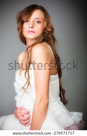 Sleep and wake up concept. Pretty young woman in curly long brown hair with pillow on gray background.