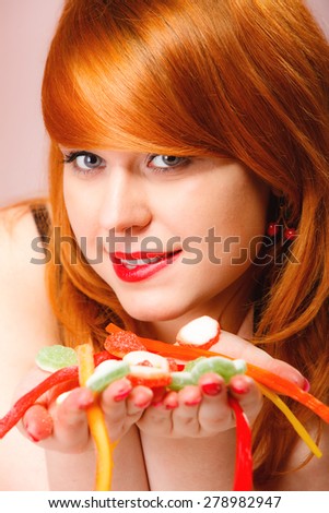 Sexy young woman holding candy. Redhair cute funny girl with sweet jelly on pink