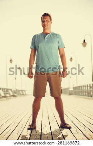 Handsome man tourist on pier. Guy enjoying summer travel vacation by sea. Fashion full length. Instagram filtered.