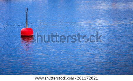 Single red buoy on calm blue sea water surface