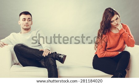Bad relationship concept. Man and woman in disagreement. Young couple after quarrel sitting on sofa