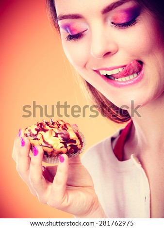 Bakery, sweet food and people concept. Woman enjoying cake cupcake licking lips orange background
