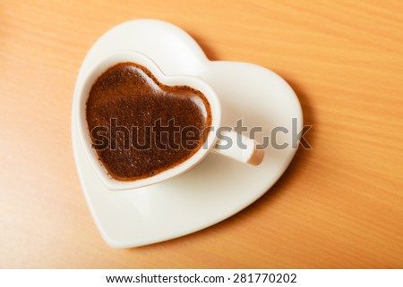 Hot coffee beverage in heart shaped cup mug on wooden board. Caffeine energy.