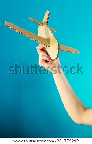 Flight travel or aerophobia concept. Female hand holding paper airplane blue background