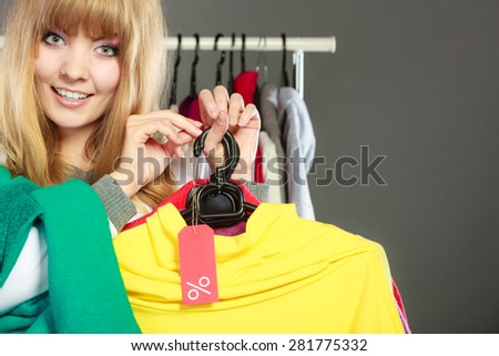 Good shopping sale concept. Blonde fashionable woman choosing clothes holding discount red label with percent sign in hand