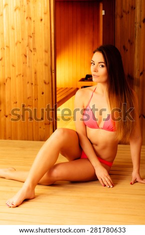Relax and rest. Young beauty woman in pink bikini resting in wood sauna.