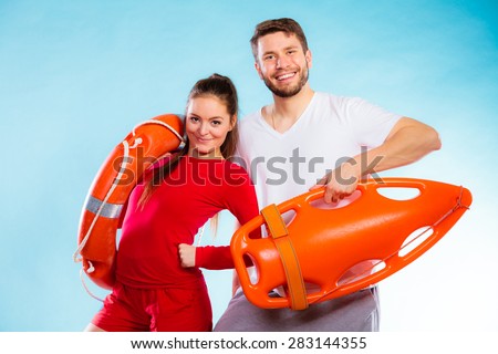 Accident prevention and water rescue. Young man and woman lifeguard couple on duty holding buoy lifesaver equipment on blue