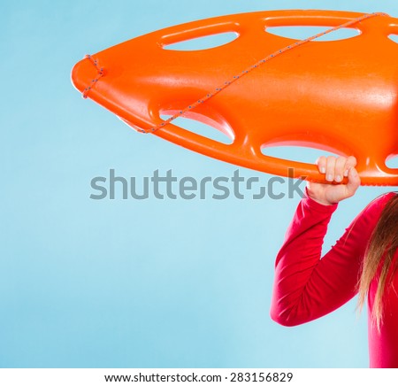 Accident prevention and water rescue. woman female lifeguard on duty holding orange float lifesaver equipment in hand on blue, copyspace