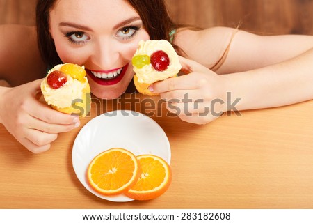 Delighted woman hiding behind table sneaking and eating delicious cake with sweet cream and fruits on top. Appetite and gluttony concept.