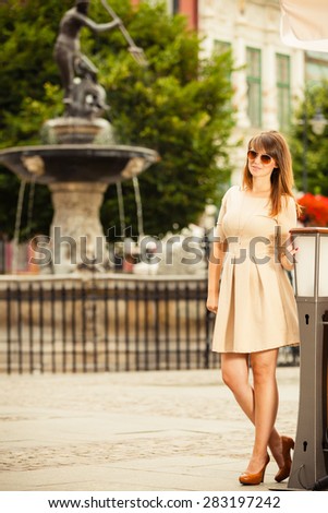 Holidays and tourism concept. Full length pretty woman in elegant dress outdoor on the street of old town european city Gdansk Danzig Neptune fountain Poland