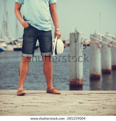 Closeup on man legs tourist on pier in port with yachts. Guy enjoying summer travel vacation by sea. Full length.