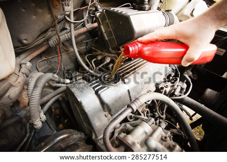 Car servicing mechanic pouring oil to engine. Closeup of fresh oil being poured into a car.