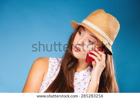 Technology and communication- confused teen girl talking on mobile phone smartphone, worried woman using cell phone on blue. Misunderstanding.