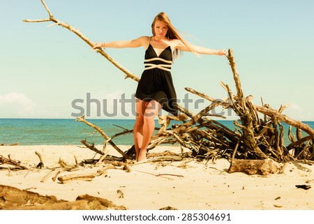 Seductive woman outdoor in summer. Sexual young model in black dress on beach.