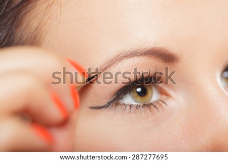 Closeup part of face, woman plucking eyebrows depilating with tweezers. Girl tweezing eyebrows.