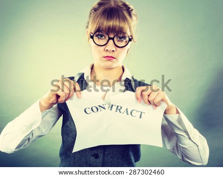 Business, documents and legal concept - serious unhappy businesswoman tearing crumpled contract