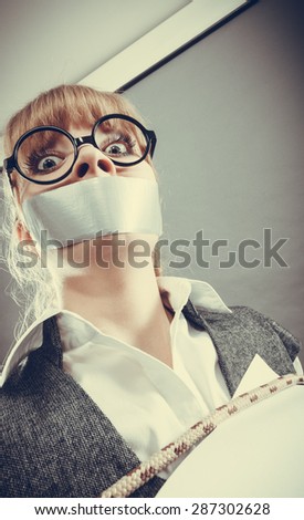 Afraid businesswoman bound by contract terms and conditions with mouth taped shut. Scared woman tied to chair become slave. Business and law concept. Instagram filtered.