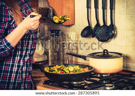 Closeup of human in kitchen cooking stir fry frozen vegetables. Person frying making delicious risotto. Dinner food meal.