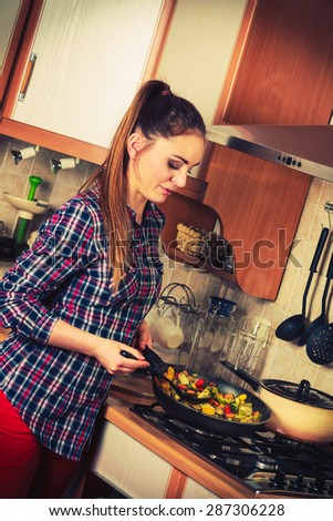 Woman in kitchen cooking stir fry frozen vegetables. Girl frying making dinner food meal. Instagram filter.