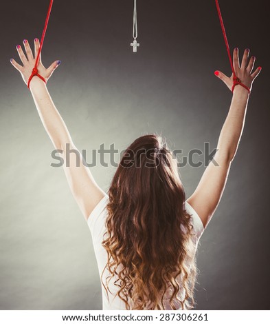 Tied woman forced to worship. Fake faith belief concept. Christian religion. Girl praying to god because of society pressure.