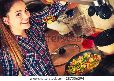 Woman in kitchen cooking stir fry frozen vegetables and tasting. Girl frying making delicious dinner food meal. Instagram filtered.