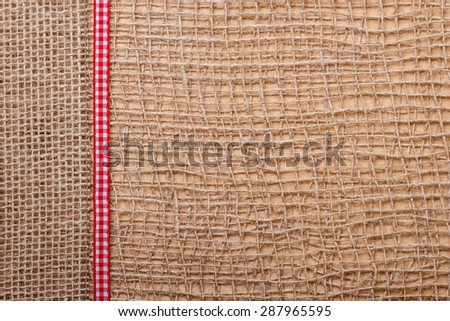 Red checked ribbon on brown mesh jute material, natural burlap ecology background