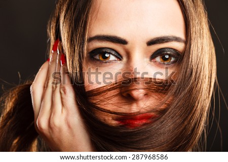 Beauty and good looking female. Pretty woman face with hand holding hair on lips. Studio shot on grey background.