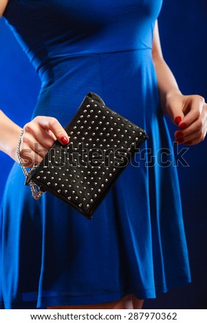 Fashion elegant evening outfit. Close up female hand holding black rivet leather handbag bag