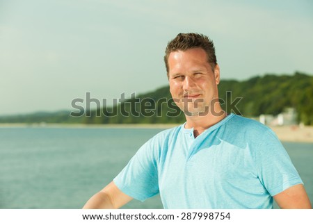 Handsome man tourist on pier. Guy enjoying summer travel vacation by sea. Fashion.