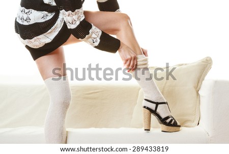 Fashionable woman legs. Girl in striped dress puts on woolen stockings indoor at home