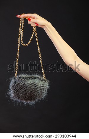 Fashion. Woman hand red nails holding evening small round gray handbag on black background