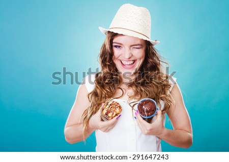 Bakery, sweet food and people concept. Closeup crazy summer woman curly hair straw hat holding cakes cupcakes on breast blue background