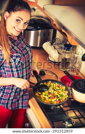 Woman in kitchen cooking stir fry frozen vegetables. Girl frying making delicious dinner food meal. Instagram filter.