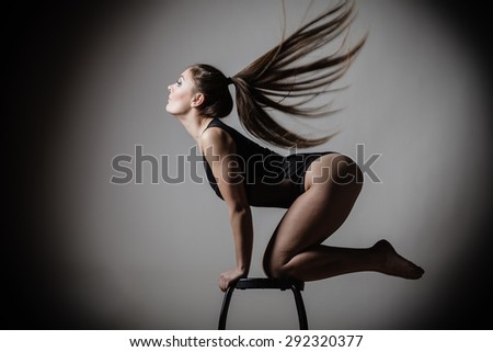 Bodybuilding. Atletic woman fit slim body posing with hair blowing on dark background