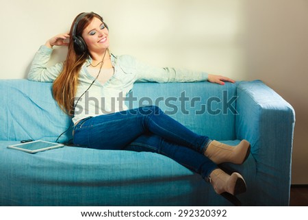 Modern technologies leisure and lifestyle concept. attractive woman student girl with headphones sitting on blue couch using tablet