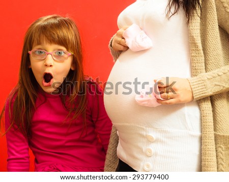 Pregnancy and family concept. Pregnant woman awaiting her second child, wide eyed little girl with amazed face expression looking at tummy her mom, so happy about it